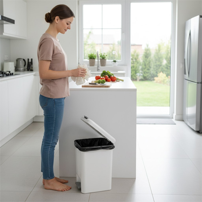 Femme devant la poubelle de cuisine, u sac à la main pour le placer à l'intérieur